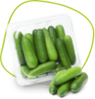 A transparent plastic container filled with fresh, small green cucumbers, with a few cucumbers placed outside the container on a flat surface. The background is a vibrant, stylized green and yellow pattern. GREENHOUSE Goodness